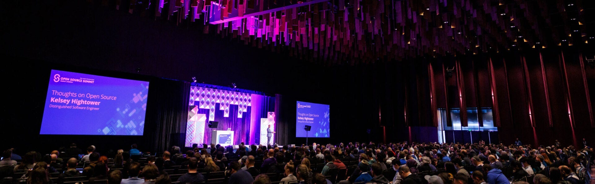 A speaker on stage in the keynote room with a large audience.